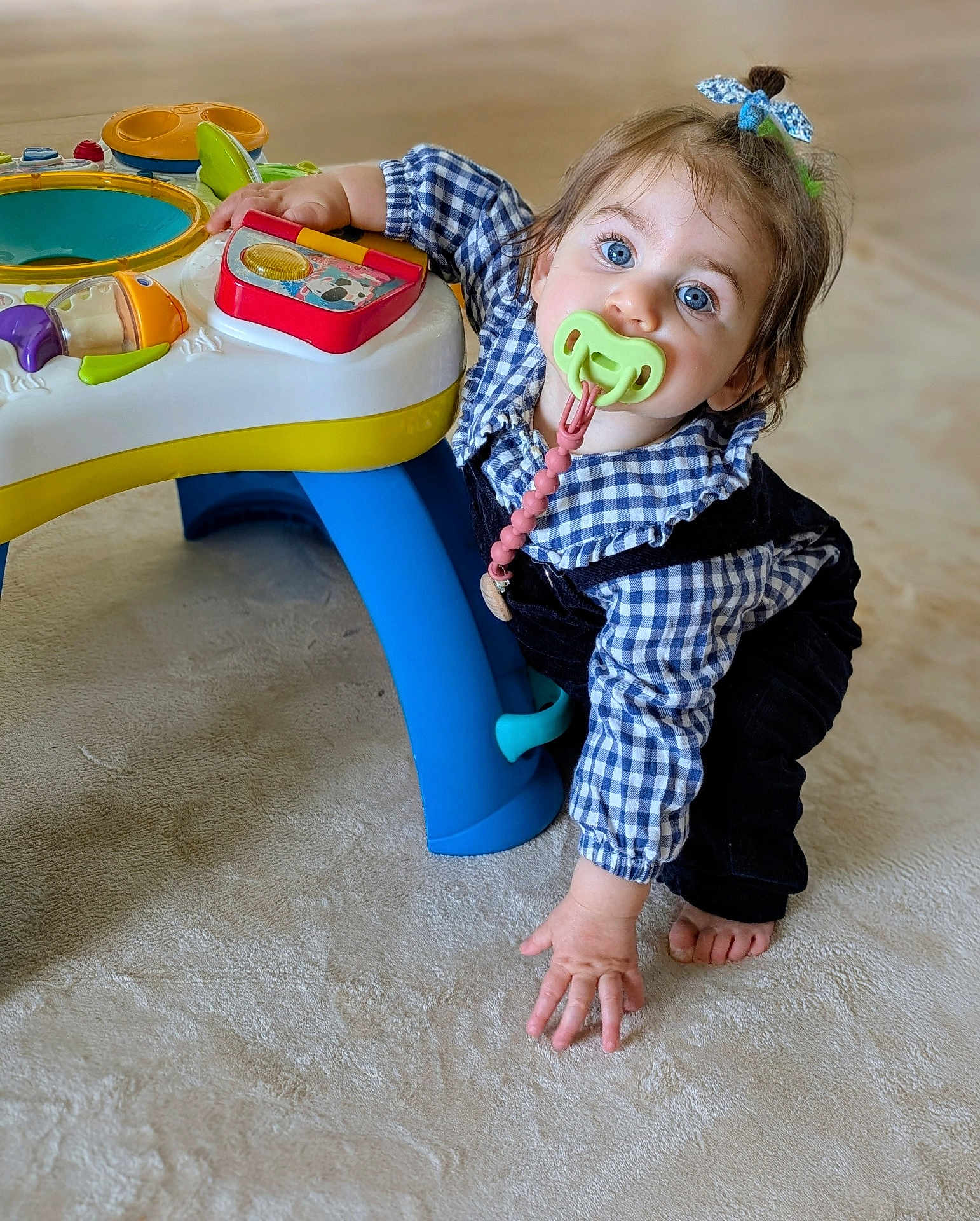 Calixte a rejoint le concours — aidez-le/la à gagner de superbes lots ! toddler, child, pacifier, toy, floor, blue_eyes, hair_tie, indoor, plaid_shirt, overalls, curious, crawling, baby_toy, colorful, hand, foot, carpet, person, playing, cute
