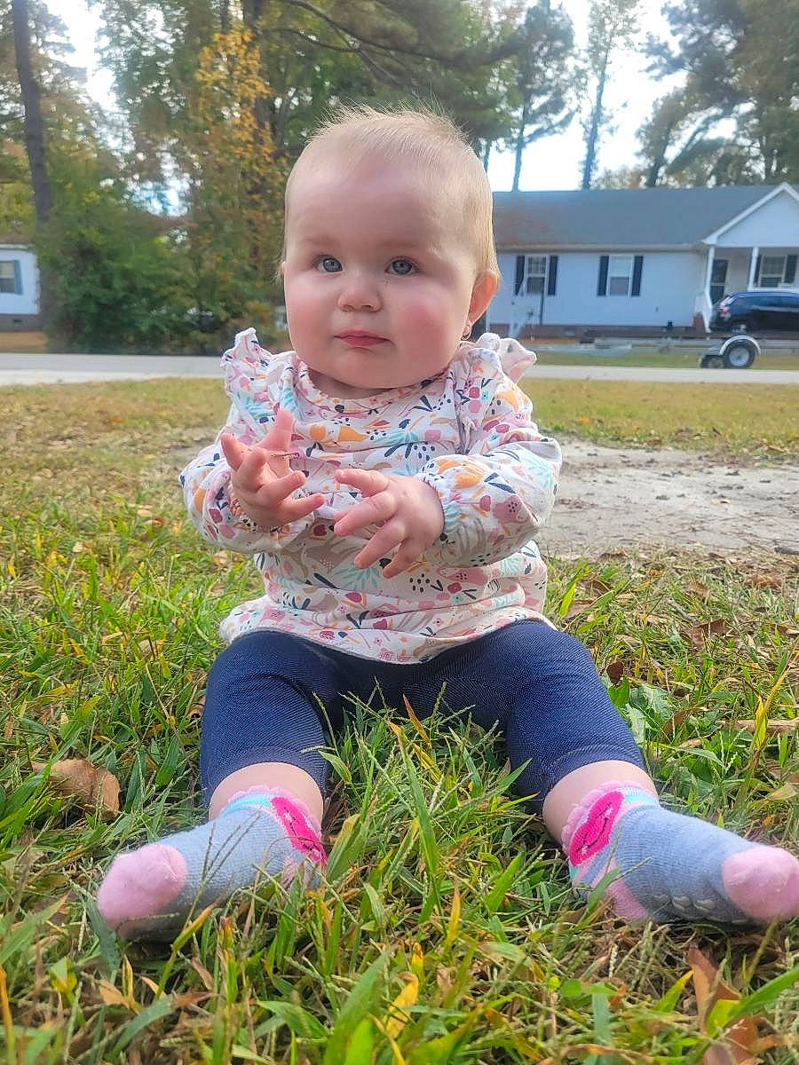 Ava is registered to the contest to win money with this photo: baby, baby_toddler_clothing, child, fun, garden, grass, grass_family, happy, head, lawn, meadow, people_in_nature, person, pink, plant, sitting, tire, toddler, tree, truck