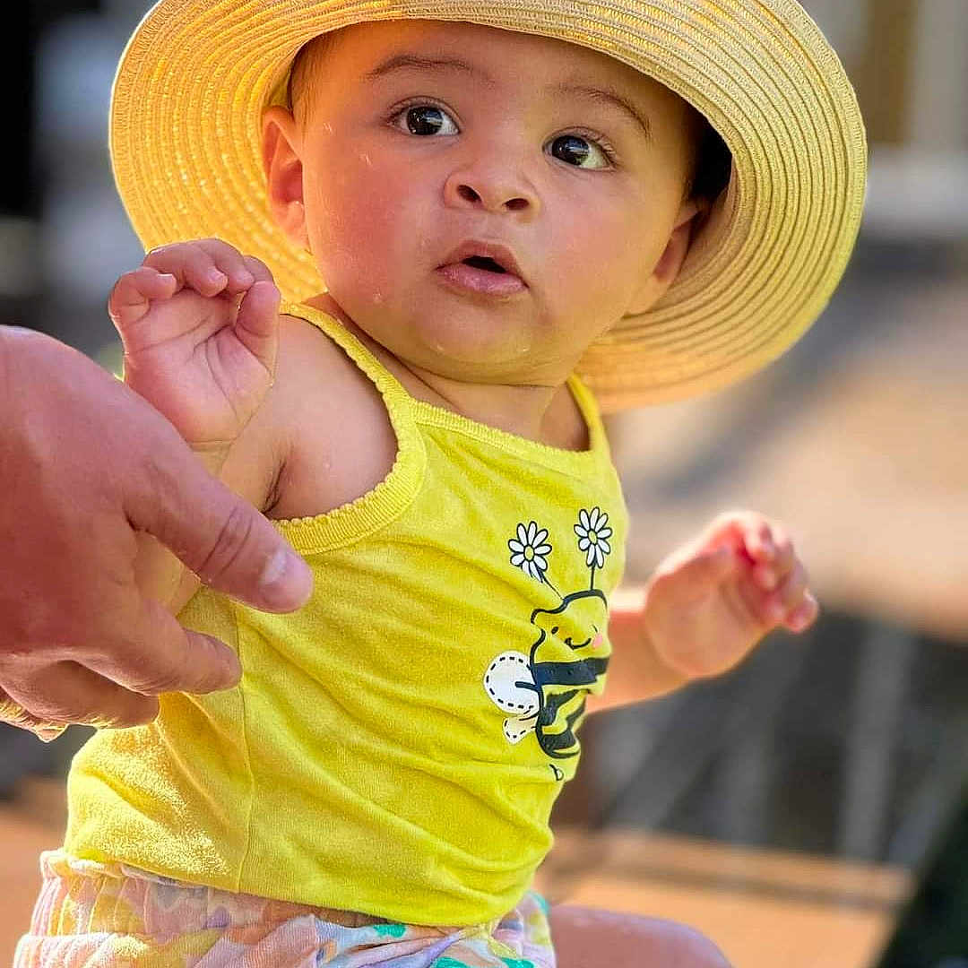 Ophelia joined the competition — help win amazing prizes! baby, beachwear, bodypart, cap, clothing, face, finger, frown, hand, hat, head, person, photography, portrait, sad, shorts, sitting, sleeve, sunhat, t_shirt