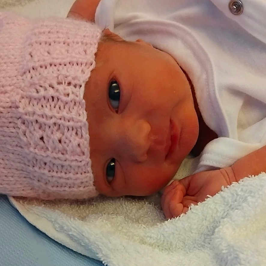 Sophia joined the competition — help win amazing prizes! baby, baby_gaze, blue_background, cozy, cute, eyes, face, hand, indoors, infant, knitted_hat, lying_down, newborn, newborn_clothing, pink_hat, portrait, resting, skin, soft_texture, white_towel