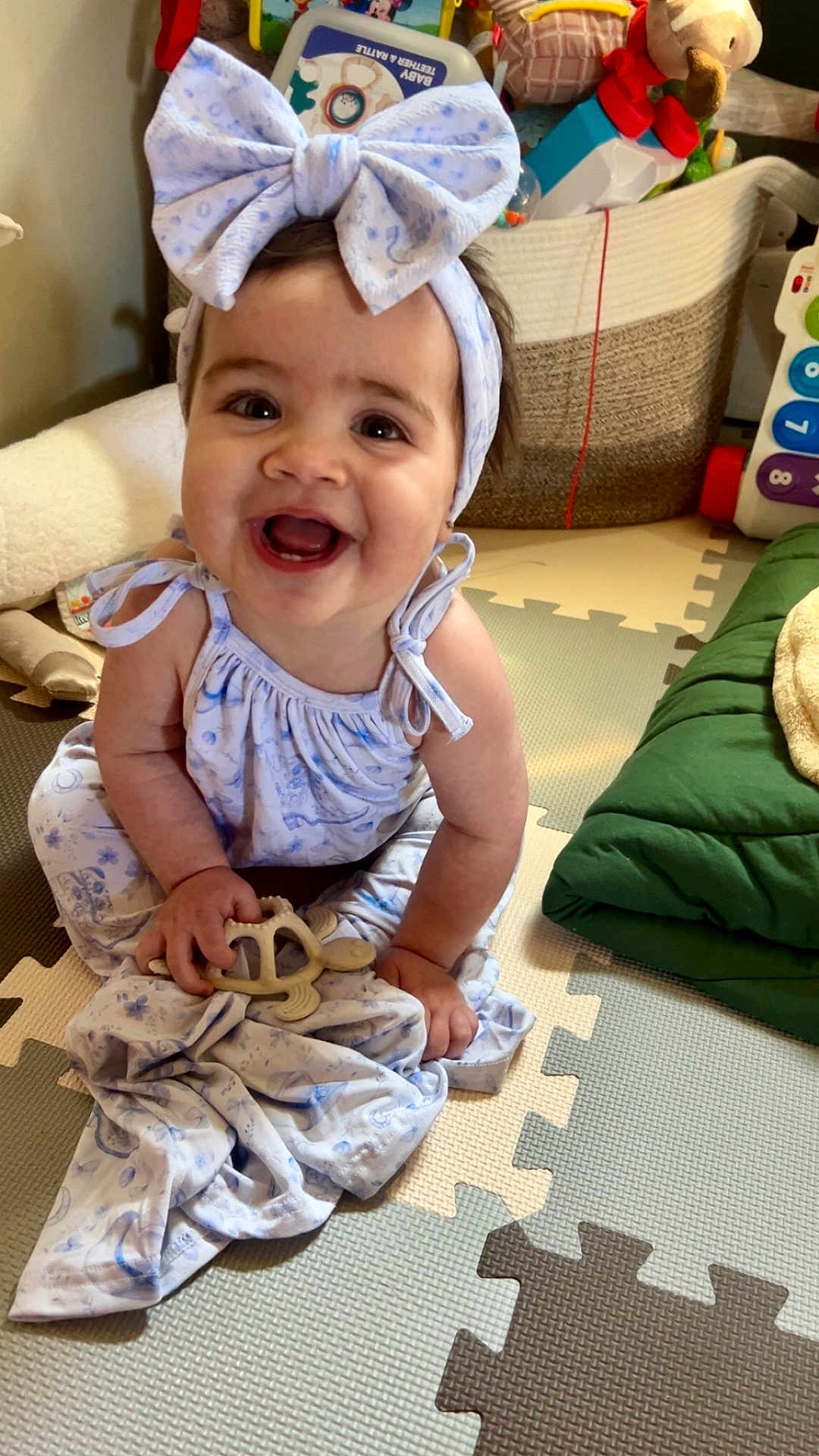 Gwen joined the competition — help win amazing prizes! baby, child, smiling, headband, bow, toy, turtle, play_mat, indoor, happy, sitting, clothing, dress, hand, face, infant, cute, colorful, floor, home