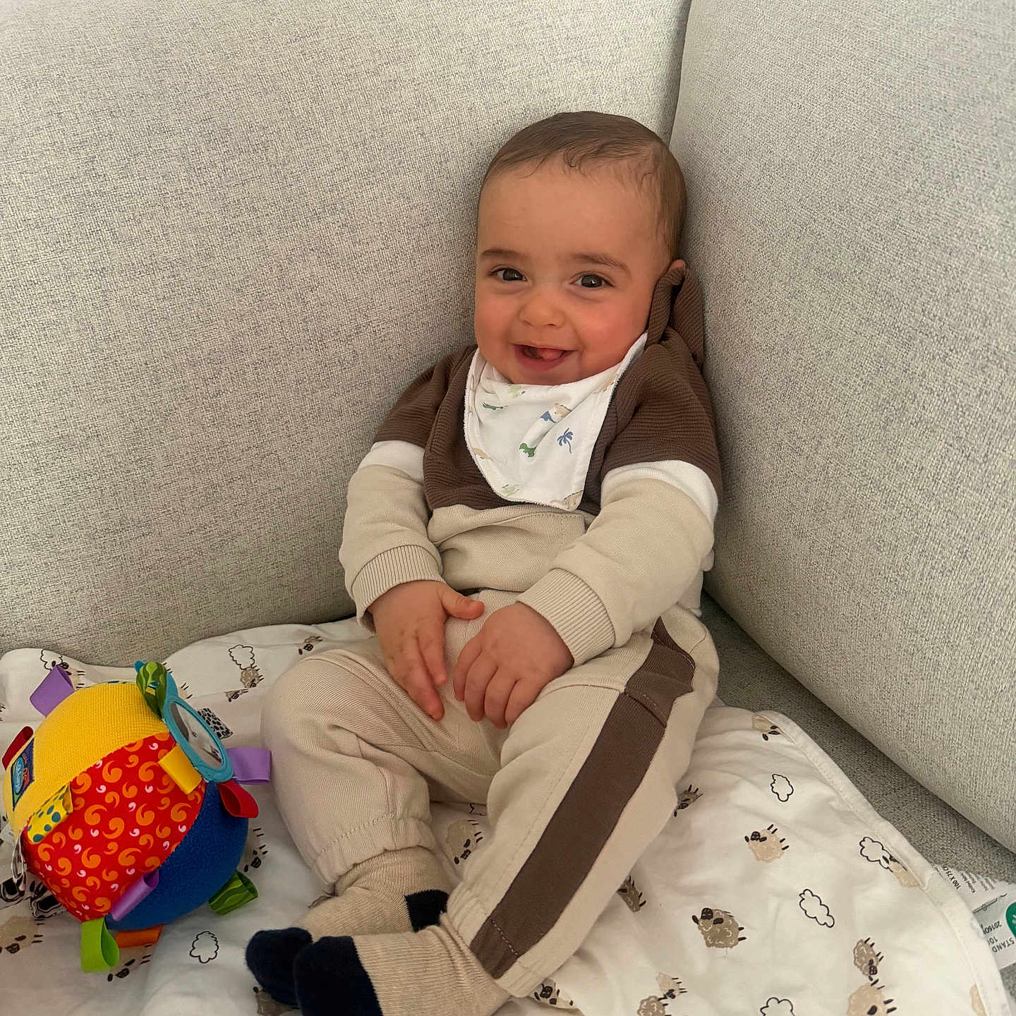 Liam a rejoint le concours — aidez-le/la à gagner de superbes lots ! baby, child, smiling, sitting, couch, blanket, toy, colorful, happy, indoor, cozy, clothing, socks, face, person, comfort, cute, infant, playful, fabric