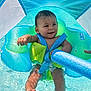 Luka is registered to the contest to win money with this photo: baby, child, pool, water, inflatable_ring, float, blue, green, swimming, summer, outdoor, shade, wet_hair, feet, playful, toy, fun, happy, infant, person