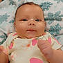 Ember is registered to the contest to win money with this photo: baby, infant, face, blanket, pattern, onesie, flower, strawberry, cute, smile, skin, hand, lying, cozy, indoors, sparkle_effect, child, adorable, soft, young