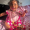 baby, child, smiling, pink_dress, socks, pacifier, blanket, patterned_blanket, sunlight, shadow, indoor, face, happy, cute, sitting, infant, curly_hair, toy, playful, portrait