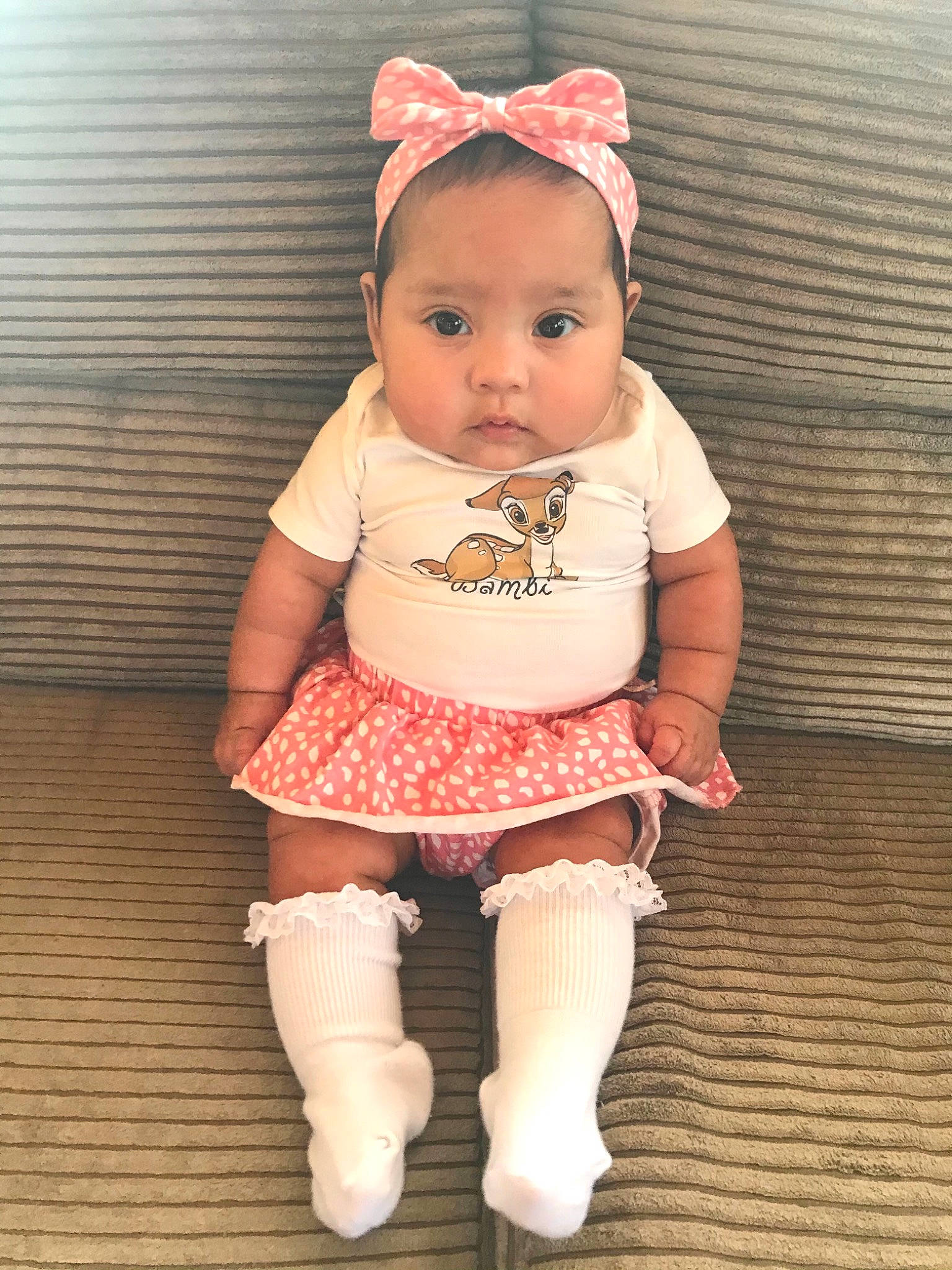 Alora is registered to the contest to win money with this photo: arm, baby, baby_toddler_clothing, cheek, chin, eye, face, floor, flooring, human_body, iris, lip, outerwear, person, pink, skin, sleeve, sock, thigh, toddler