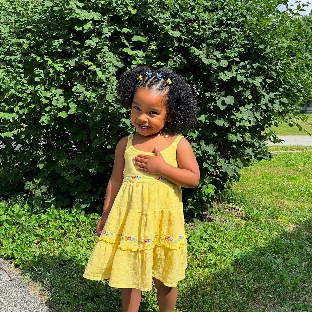 Anias joined the competition — help win amazing prizes! child, girl, yellow_dress, outdoor, grass, bush, smile, curly_hair, hair_clips, sunny, sandals, greenery, standing, nature, happy, portrait, person, summer, cute, fashion