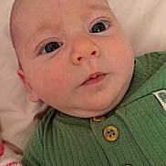 Elliot is registered to the contest to win money with this photo: baby, infant, child, portrait, close_up, face, eyes, wide_eyed, cozy, green_outfit, ribbed_clothing, wooden_buttons, bedding, blanket, indoor, lying_down, soft_lighting, candid, cute, photography