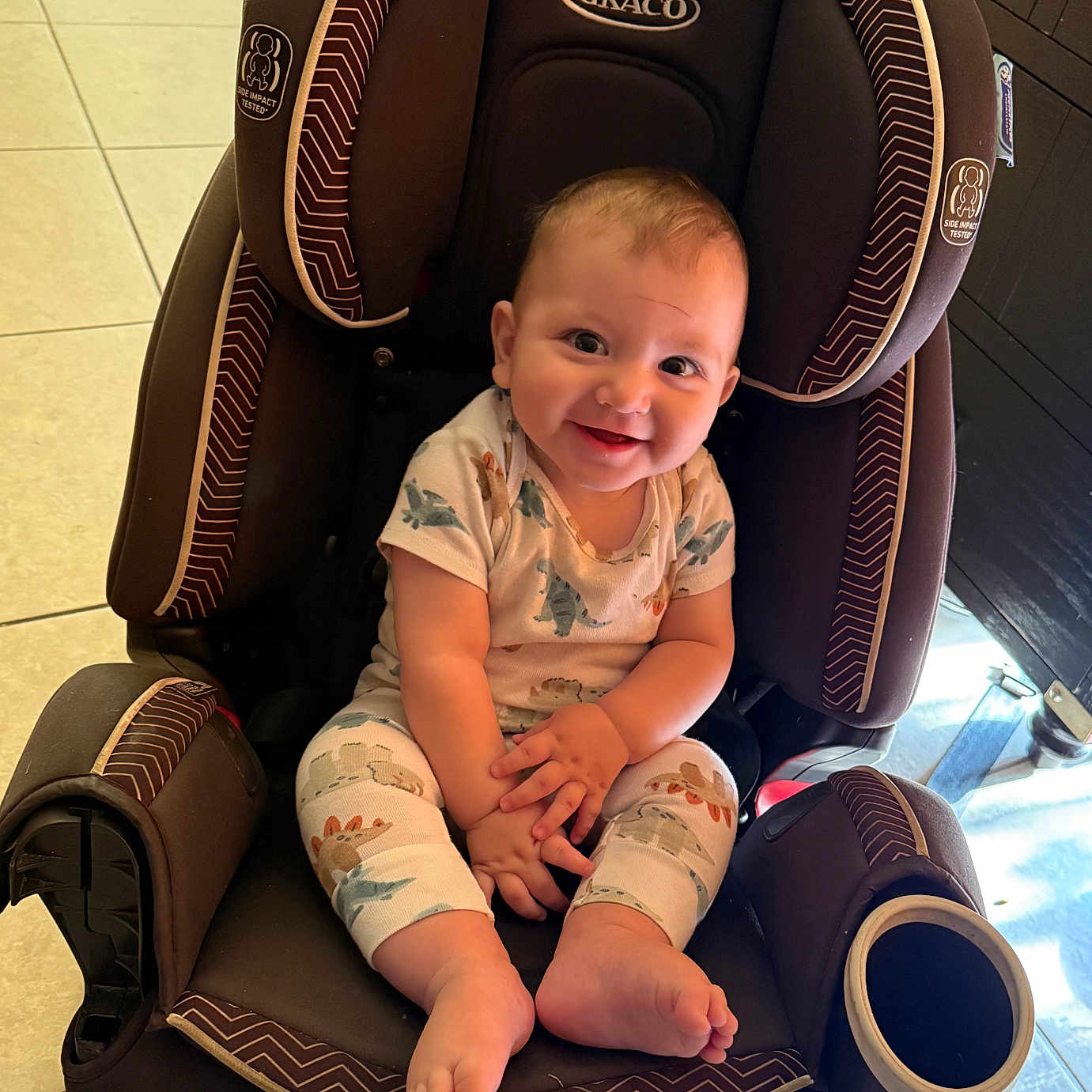 Elliot is registered to the contest to win money with this photo: baby, child, infant, smiling, happy, portrait, car_seat, sitting, indoors, floor, tile, clothing, onesie, bare_feet, blond_hair, face, eyes, graco, cup_holder, family_photo