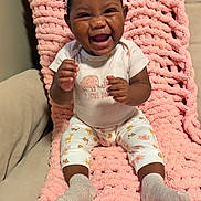 Jayloni is registered to the contest to win money with this photo: baby, child, infant, smiling, laughing, portrait, indoor, pink_blanket, knitted_blanket, bow, headband, onesie, elephant_pattern, patterned_pants, socks, seated, happy, cozy, couch, family_photo