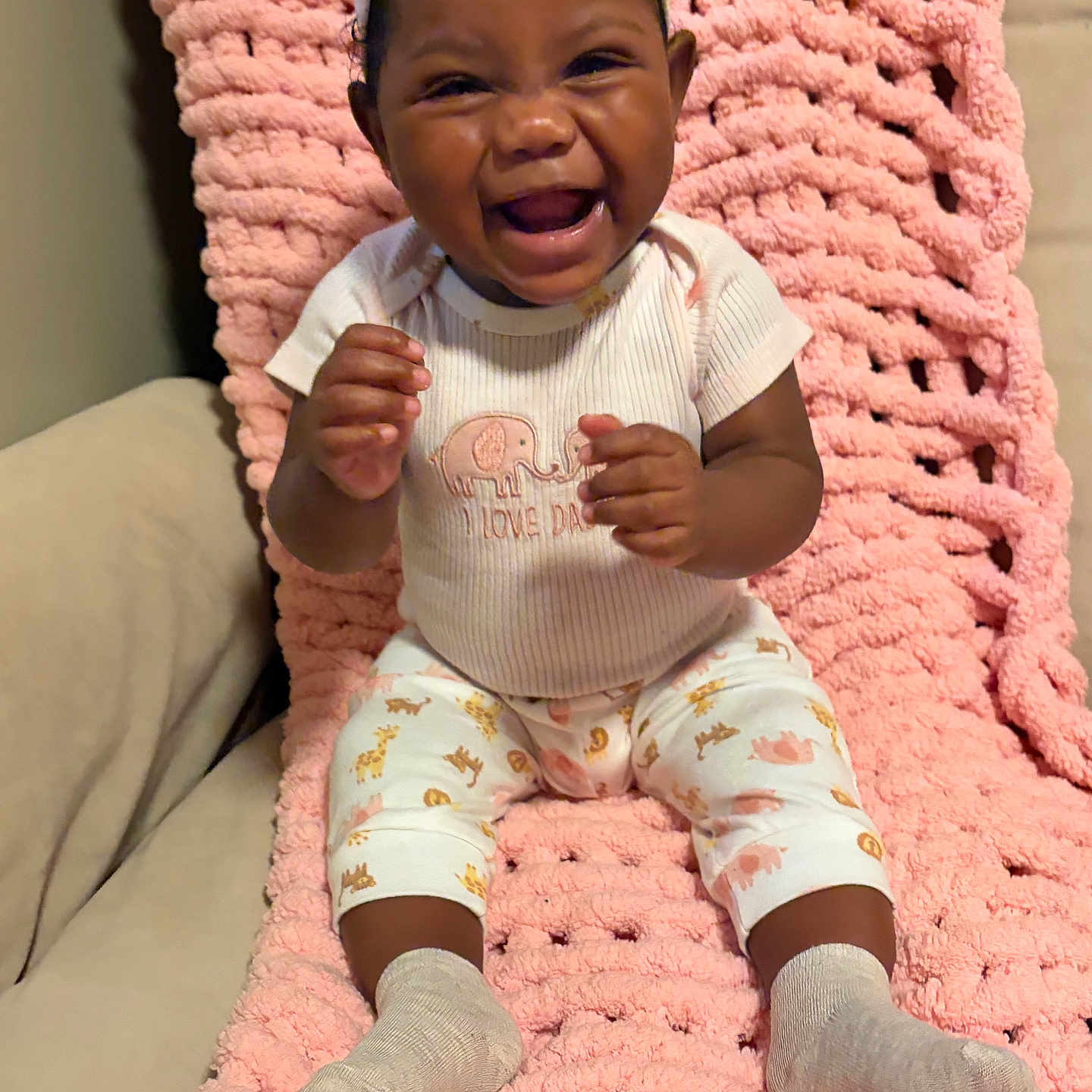 Jayloni is registered to the contest to win money with this photo: baby, child, infant, smiling, laughing, portrait, indoor, pink_blanket, knitted_blanket, bow, headband, onesie, elephant_pattern, patterned_pants, socks, seated, happy, cozy, couch, family_photo