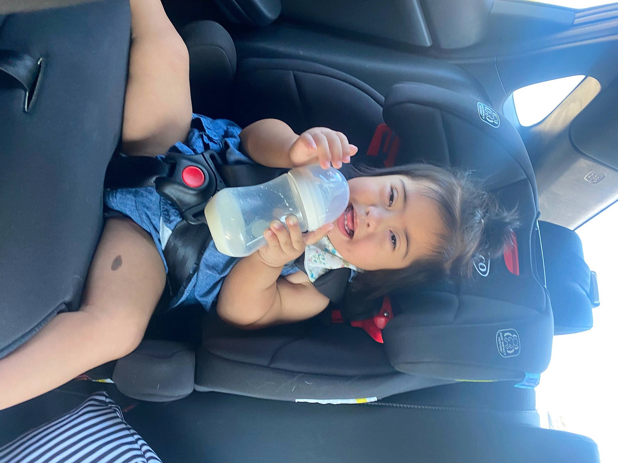 Ofelia is registered to the contest to win money with this photo: arm, automotive_design, baby, baby_carriage, baby_in_car_seat, car, car_seat, car_seat_cover, dress, finger, human_body, leg, motor_vehicle, mouth, person, skin, steering_part, thigh, toddler, vehicle