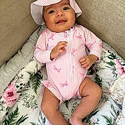 Alya a rejoint le concours — aidez-le/la à gagner de superbes lots ! baby, infant, smiling, hat, onesie, pink, floral_blanket, couch, cozy, hand, toes, eyes, portrait, indoor, fabric, pattern, zipper, headwear, soft_texture, relaxed