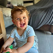 Evy a rejoint le concours — aidez-le/la à gagner de superbes lots ! blurred_background, book, child, cute, face, floor, furniture, hair, happy, home, indoor, joy, natural_light, person, playful, shorts, sitting, smiling, toddler, tshirt