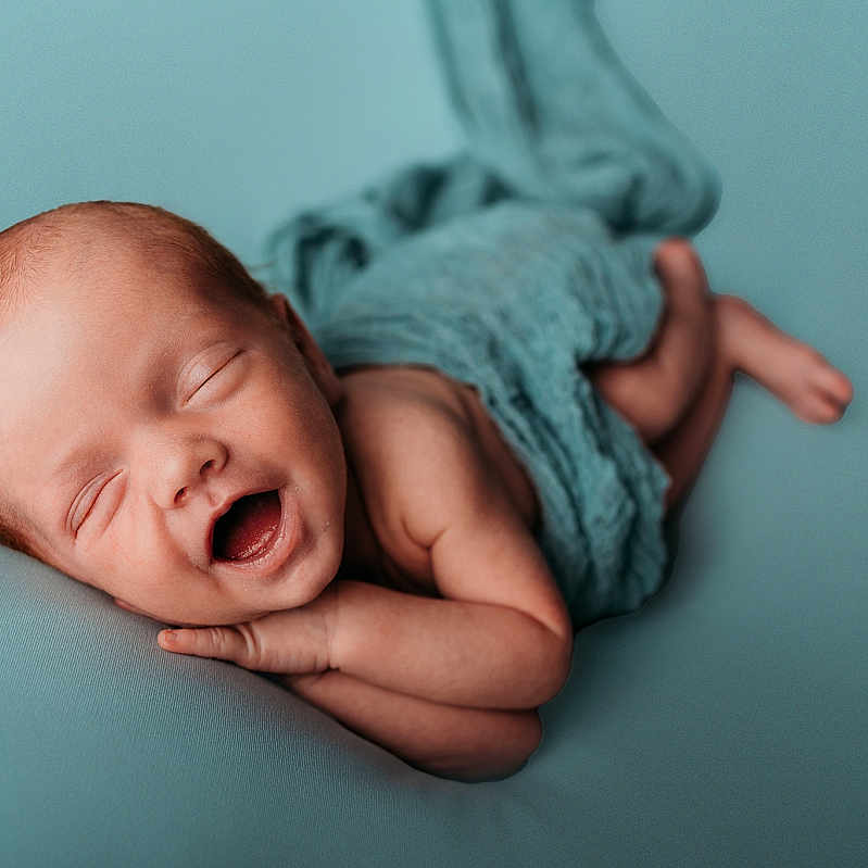 Tait is registered to the contest to win money with this photo: arm, baby, blue_background, child, cute, foot, hand, happy, head, infant, lying_down, newborn, peaceful, portrait, skin, sleeping, smiling, soft_texture, tiny, wrapped