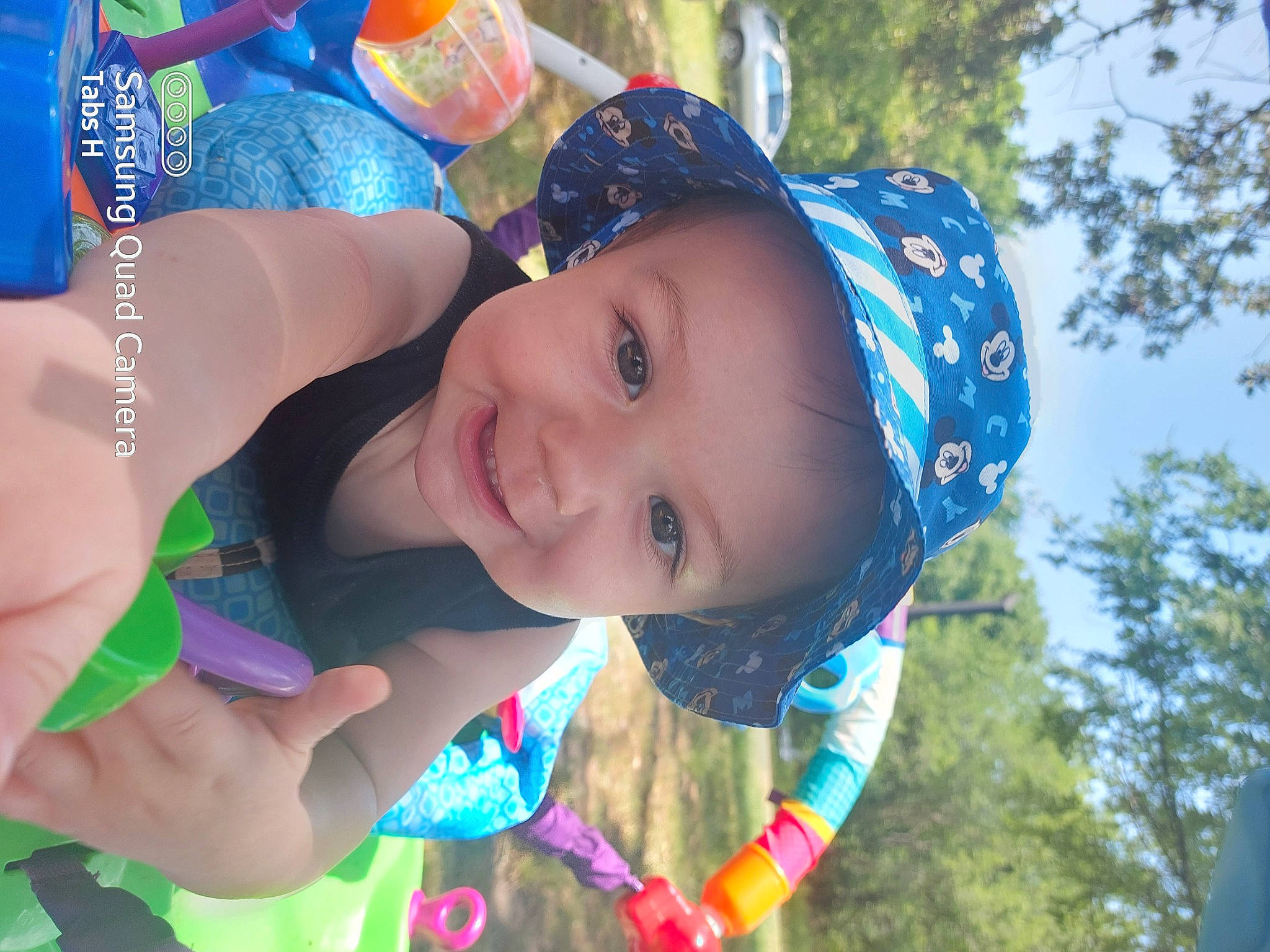 Talyn is registered to the contest to win money with this photo: baby, blue, cap, cool, facial_expression, fun, grass, happy, headwear, human, joy, leisure, outdoor_recreation, people_in_nature, person, pink, plant, recreation, sky, smile