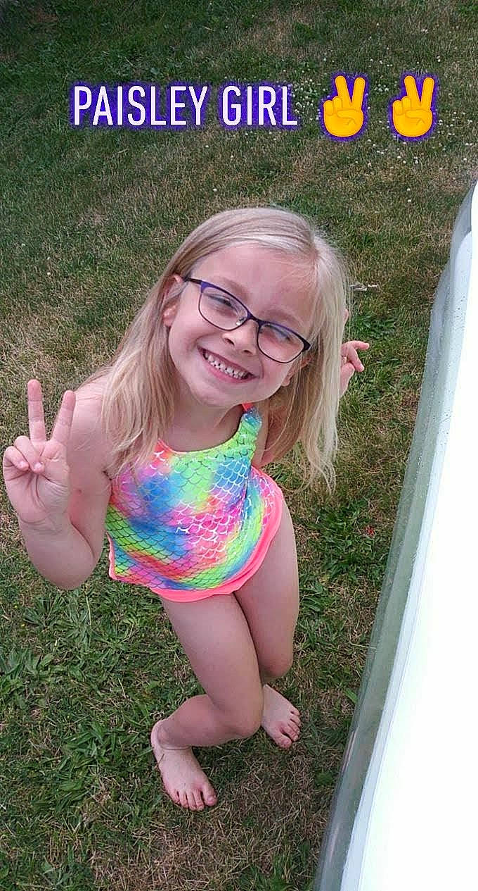 Paisley is registered to the contest to win money with this photo: baby_toddler_clothing, facial_expression, finger, fun, gesture, grass, hairstyle, happy, joy, leg, leisure, one_piece_swimsuit, people_in_nature, person, pink, plant, skin, smile, summer, thigh