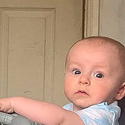 Wyatt joined the competition — help win amazing prizes! baby, child, indoor, toy, steering_wheel, curious, wide_eyes, infant, face, arm, clothing, door, handle, expression, person, play, young, cute, light, background