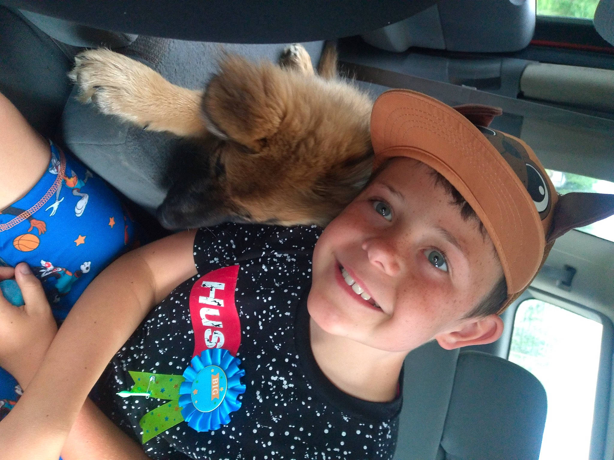 Jaxsyn is registered to the contest to win money with this photo: blond, blue, cap, car_seat, child, electric_blue, finger, fun, gesture, happy, headgear, headwear, human_leg, joy, leisure, nail, person, smile, snapshot, thigh