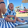 baby, beach, towel, child, sunshine, smile, umbrella, sand, lounge_chair, summer, vacation, outdoor, people, blue_sky, happy, clothing, barefoot, holiday, relaxation, waterfront