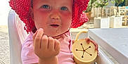 Sofia joined the competition — help win amazing prizes! baby, child, pink_hat, polka_dot, high_chair, outdoor, sunlight, cup, curious_expression, face, hand, clothing, seat, table, summer, sun_protection, toddlers, cute, food_crumb, daytime