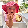 baby, child, pink_hat, polka_dot, high_chair, outdoor, sunlight, cup, curious_expression, face, hand, clothing, seat, table, summer, sun_protection, toddlers, cute, food_crumb, daytime