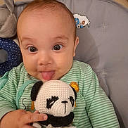 Kénaï participe au concours pour gagner de l'argent avec cette photo : baby, child, closeup, crocheted, cushion, cute, expression, face, green_striped_clothing, hand, home, indoor, infant, panda, person, playful, seat, smile, tongue, toy