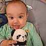 baby, child, closeup, crocheted, cushion, cute, expression, face, green_striped_clothing, hand, home, indoor, infant, panda, person, playful, seat, smile, tongue, toy