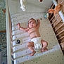 baby, crib, diaper, toy, nursery, plush_toy, infant, sleeping_area, child, patterned_wallpaper, wooden_crib, playful, cute, lying_down, baby_bedding, indoor, soft_toys, baby_girl_or_boy, childcare, room_decor
