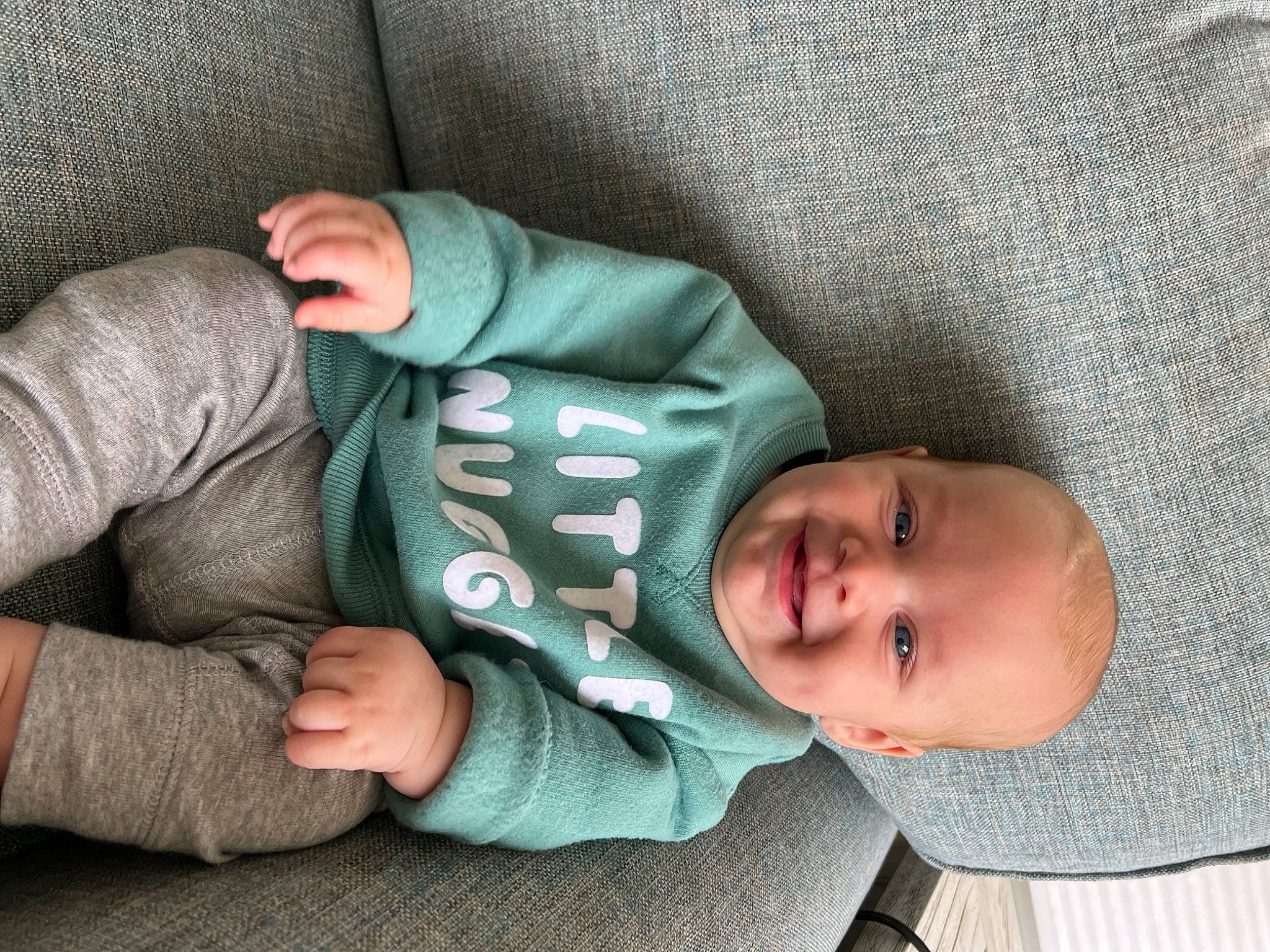 Bentley is registered to the contest to win money with this photo: arm, baby, baby_products, baby_sleeping, baby_toddler_clothing, cheek, child, comfort, finger, gesture, hand, human_body, joy, linens, nap, person, sitting, skin, sleeve, smile