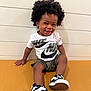 toddler, child, smiling, curly_hair, afro, nike, sneakers, shorts, tshirt, bench, indoor, portrait, happy, young_child, casual_clothing, footwear, person, seated, cute, playful