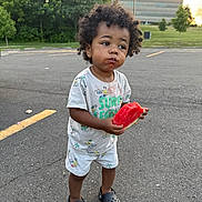Tylin joined the competition — help win amazing prizes! toddler, child, watermelon, curly_hair, outdoor, parking_lot, asphalt, shorts, tshirt, crocs, food, summer, greenery, building, sunset, casual_clothing, cute, messy_face, holding, standing