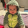 baby, child, dinosaur_onesie, hood, smile, sitting, bed, blanket, gloves, socks, indoor, cute, happy, face, person, clothing, cozy, soft, infant, portrait