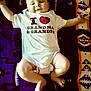 Lucas is registered to the contest to win money with this photo: baby, infant, onesie, text_on_clothing, blanket, patterned_blanket, lying_down, arms_outstretched, happy, smiling, face, legs, feet, child, person, indoors, cute, soft_lighting, closeup, portrait