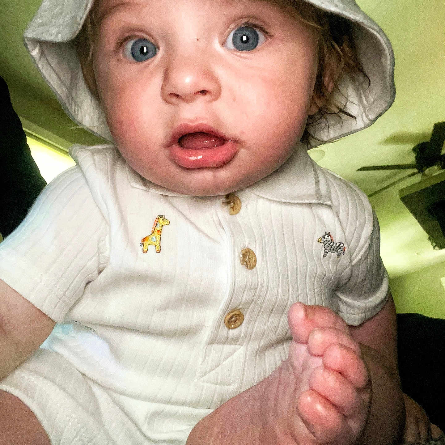 Patrick is registered to the contest to win money with this photo: baby, bodypart, bonnet, cap, clothing, dress, face, finger, hand, hat, head, mouth, newborn, pants, person, photography, portrait, sitting, sunhat, t_shirt