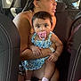 baby, child, woman, car, seat, pacifier, braids, floral_dress, pink_socks, holding, portrait, indoor, seatbelt, person, candid, expression, human, clothing, transportation, family