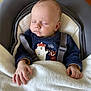 baby, sleeping, blanket, baby_seat, clothing, infant, peaceful, cute, navy_blue, animal_print, face, hand, close_up, indoor, soft_light, portrait, child, newborn, cozy, rest