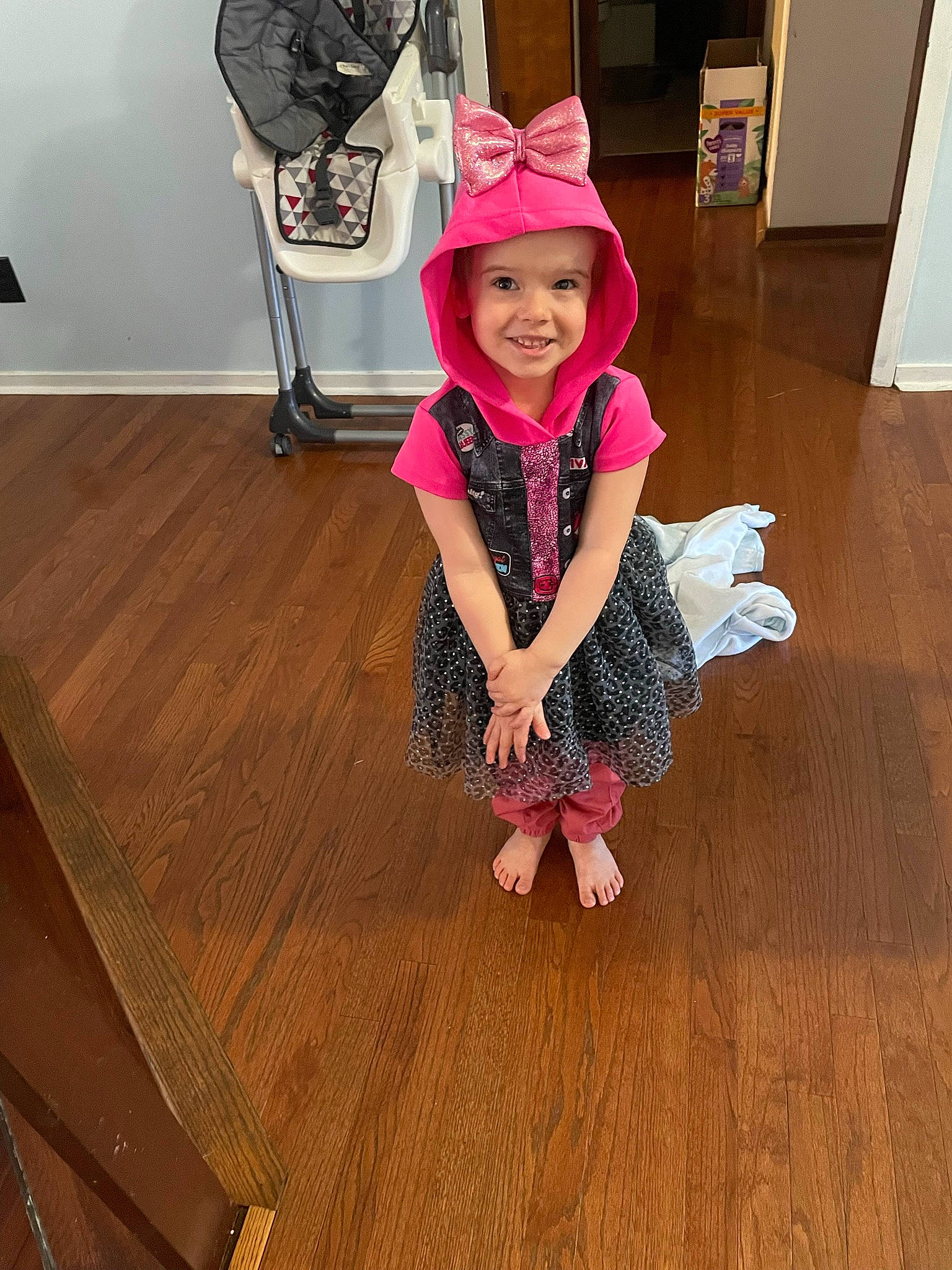 Evelyn is registered to the contest to win money with this photo: baby_toddler_clothing, costume_hat, floor, flooring, fun, happy, hardwood, hat, headwear, human_leg, joy, laminate_flooring, person, plank, purple, smile, sun_hat, t_shirt, toddler, varnish