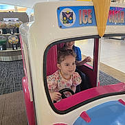 Elif joined the competition — help win amazing prizes! child, toddler, boy, girl, smiling, sitting, toy_vehicle, ice_cream, mall, indoor, play_ride, steering_wheel, colorful, portrait, family, candy_machine, giant_cone, clothing, vehicle, happy