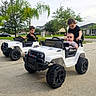 Yusuf Eren is registered to the contest to win money with this photo: children, baby, siblings, toy_cars, jeeps, ride_on_vehicle, outdoor, driveway, suburban, family, portrait, smiling, sitting, standing, curly_hair, infant, playtime, palm_trees, house, vehicles