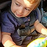 toddler, child, car_seat, buckled_in,  안전, face, portrait, curious, looking_down, brown_hair, red_hair, sunlight, indoor, vehicle, toy, colorful_toy, purple_shirt, baby, sitting, photography