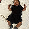 Denim is registered to the contest to win money with this photo: baby, child, infant, black_clothing, shorts, shirt, socks, blanket, lying_down, smiling, happy, cute, person, indoor, soft_texture, skin, hair, face, small_hands, playful