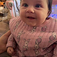 Rosemary joined the competition — help win amazing prizes! baby, child, smiling, pink_clothing, bunny_print, indoor, person, close_up, happy, cute, infant, young_child, portrait, hand, soft_lighting, face, sitting, warm_colors, blurred_background, cozy