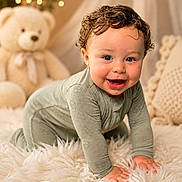 Shiloh is registered to the contest to win money with this photo: baby, child, crawling, smiling, curly_hair, drool, blue_eyes, fluffy_rug, teddy_bear, pillow, cozy, indoors, portrait, cute, soft_lighting, bokeh, warm_colors, homedecor, infant, happy