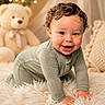 baby, child, crawling, smiling, curly_hair, drool, blue_eyes, fluffy_rug, teddy_bear, pillow, cozy, indoors, portrait, cute, soft_lighting, bokeh, warm_colors, homedecor, infant, happy