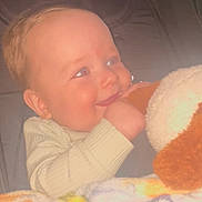 Lorenzo is registered to the contest to win money with this photo: baby, child, smiling, stuffed_animal, blanket, indoor, portrait, cute, infant, clothing, seat, phone_screen, video_selection, interface, hand, face, head, happy, person, closeup