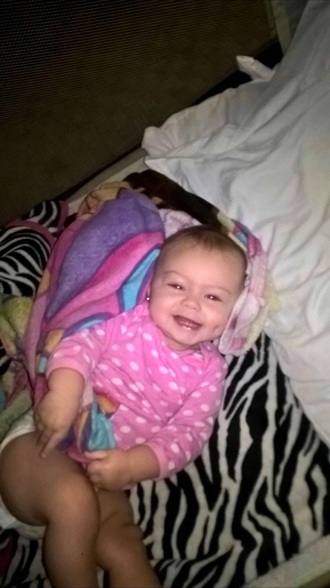 Maddilyn is registered to the contest to win money with this photo: baby, baby_products, baby_toddler_clothing, bed, bedtime, cheek, child, comfort, fun, happy, infant_bed, joy, linens, magenta, person, pink, room, sitting, sleeve, smile