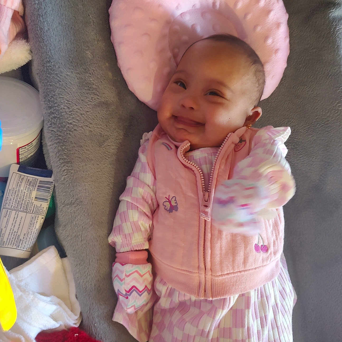 Aidee joined the competition — help win amazing prizes! apparel, baby, blanket, child, cozy, cute, face, happy, head_support, indoor, infant, lying_down, mitten, newborn, patterned_clothing, person, pillow, pink_clothing, smiling, soft_texture