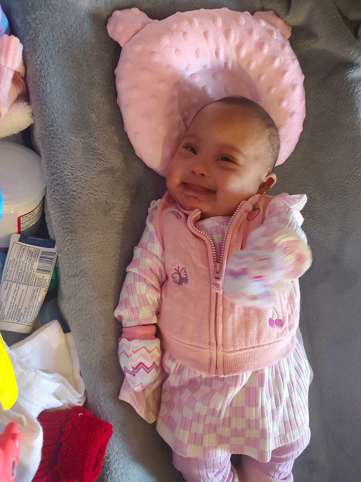 Aidee joined the competition — help win amazing prizes! baby, infant, pink_clothing, mitten, pillow, blanket, smiling, lying_down, soft_texture, indoor, cute, child, face, person, apparel, patterned_clothing, head_support, happy, newborn, cozy