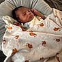 baby, sleeping, blanket, elephant_pattern, cushion, indoors, resting, child, infant, soft_fabric, comfort, peaceful, cozy, clothing, head, face, skin, person, nap, quiet